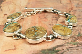 5 Beautiful Genuine Boulder Turquoise Stones set in Sterling Silver Bracelet. The cabochons are Boulder Turquoise, you can see the veins of Turquoise running through the host rock. The Boulder Turquoise Mine is located in northeast Nevada. It was discovered in 1970 by a Shoshone sheep herder. Production is small due to the remote location and winter weather. Boulder Turquoise is valued for both it's beauty and rarity. Every stone is unique. Created by Navajo Artist Tony Garcia. Signed by the artist.
